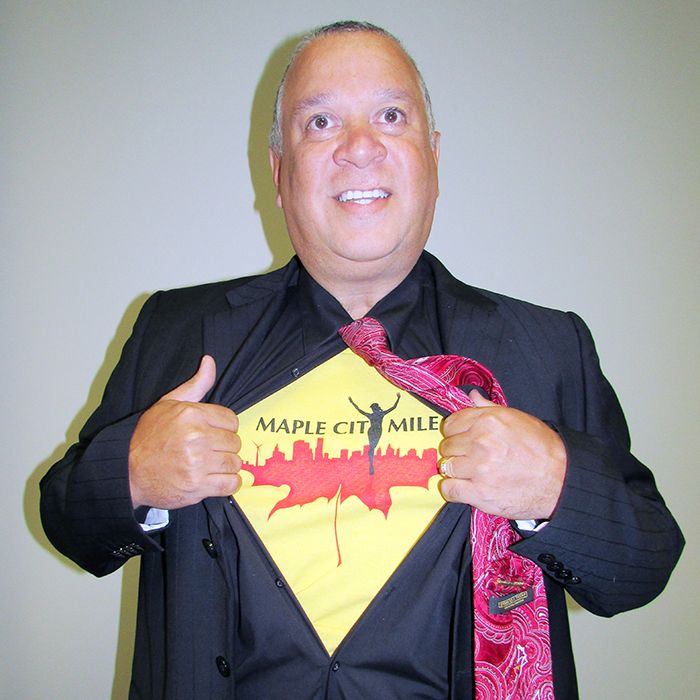 “Superman” Doug Robbins proudly rips open his dress shirt to display the Maple City Mile T-shirt underneath. 