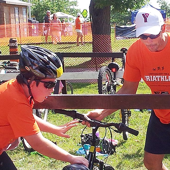 Connor McFadden, 10, of Chatham, does his best to make a clean transition from water to bike with the help of YMCA volunteer Jason Wadsworth at the annual Kids of Steel triathlon Saturday in Rondeau.