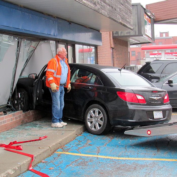 Chatham Towing personnel prepare to pull a car from a vacant storefront Friday in Chatham.