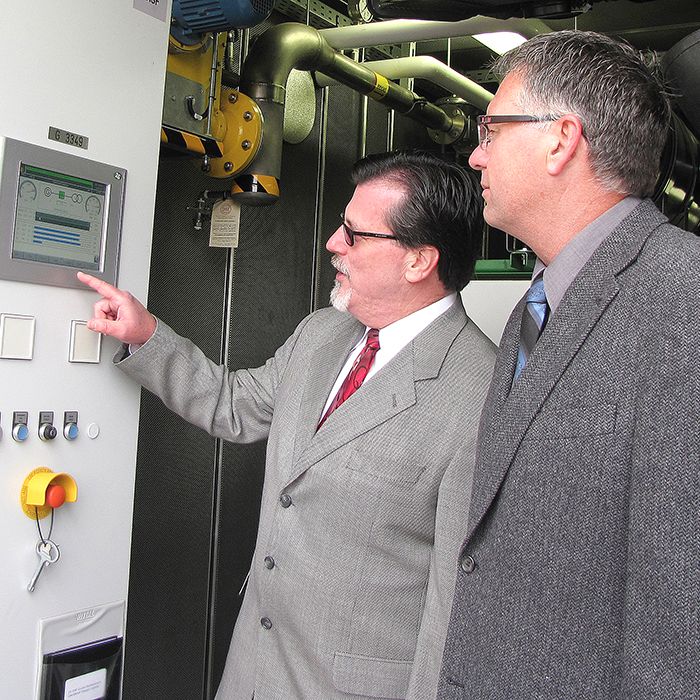 Jim Hogan, president and CEO of Entegrus Inc., left, and Tom Kissner, general manager of the Chatham-Kent PUC, look at a control panel inside a new methane-burning generator. The system, which is turning methane into electricity, is now operational at the PUC’s water pollution control plant in Chatham.