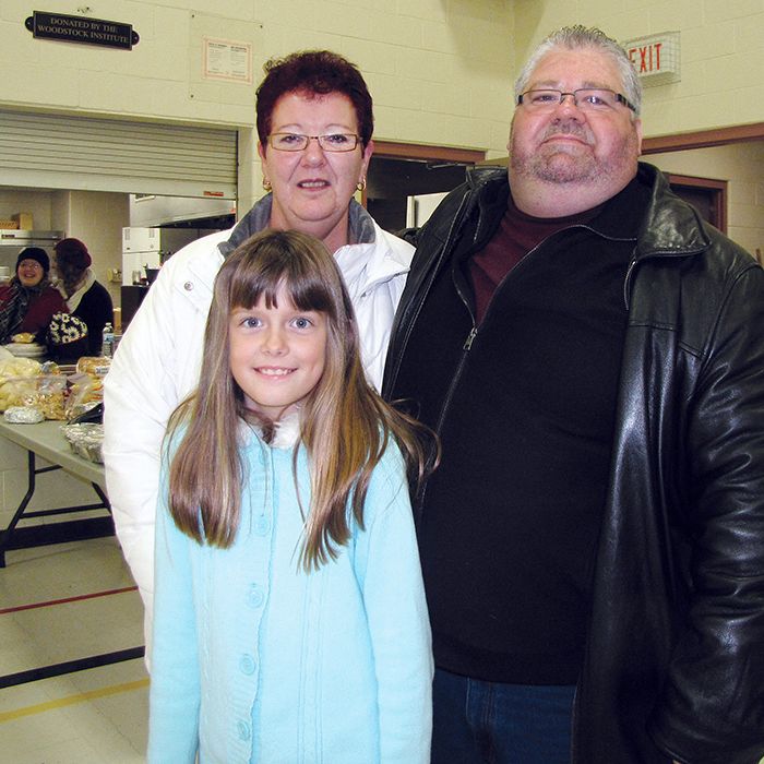 Tammy and Brent Ripley, organizers of the Community Cares Christmas dinner at the WISH Centre, are shown with eight-year-old Chantal Douglas, one of the youngest volunteers at the event. With support from area businesses and individuals, more than 600 people received a meal on Sunday.