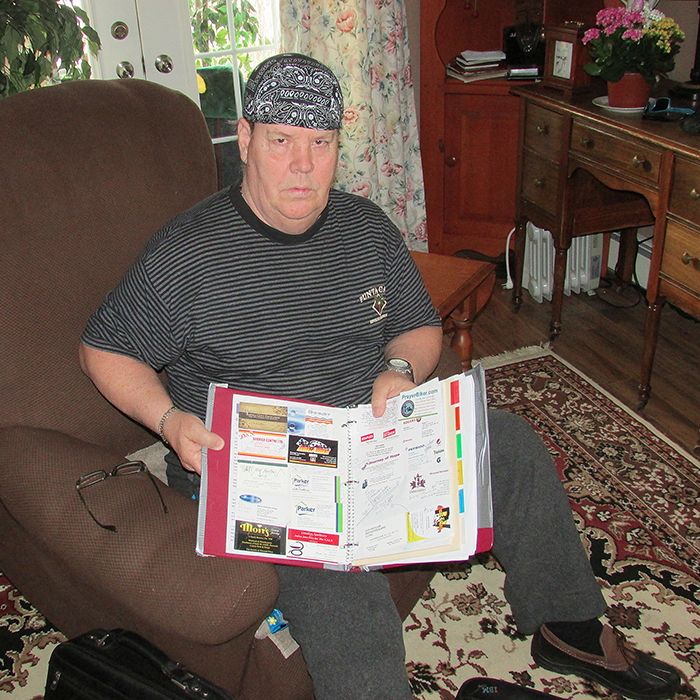 Don Wells examines a book of souvenirs from last year's Don's Journey of Hope. The 2013 event featured a scooter ride from Own Sound to Ottawa. This year Don is riding an e-bike from Wallaceburg to Owen Sound.