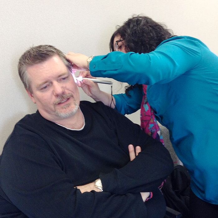 Canadian Hearing Services personnel inject putty into Bruce's ears.