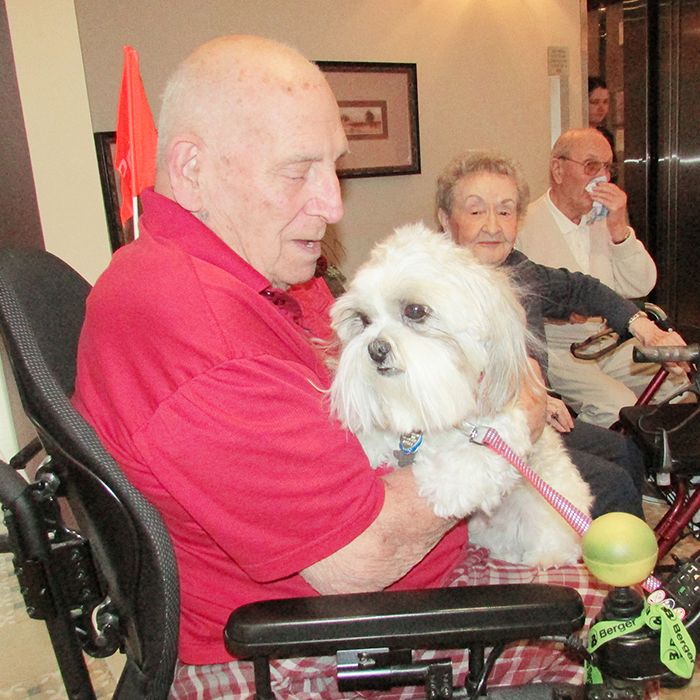 Bev Prevett cuddles with Teddy the therapy dog at Caleb Village, as Ida Trottier and Ron Smith look on.