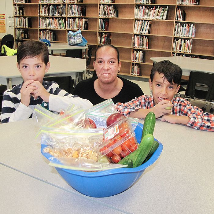John N. Given students Donavan and Marcus Lambkin enjoy a healthy snack of local fruits and vegetables that was delivered to their school through an innovative program. The area’s first Farm to School nutrition program provides locally grown, fresh fruits and vegetables to eight participating schools. Also pictured is the boys’ mother, Della Lambkin, a volunteer with the Chatham-Kent Student Nutrition Program.