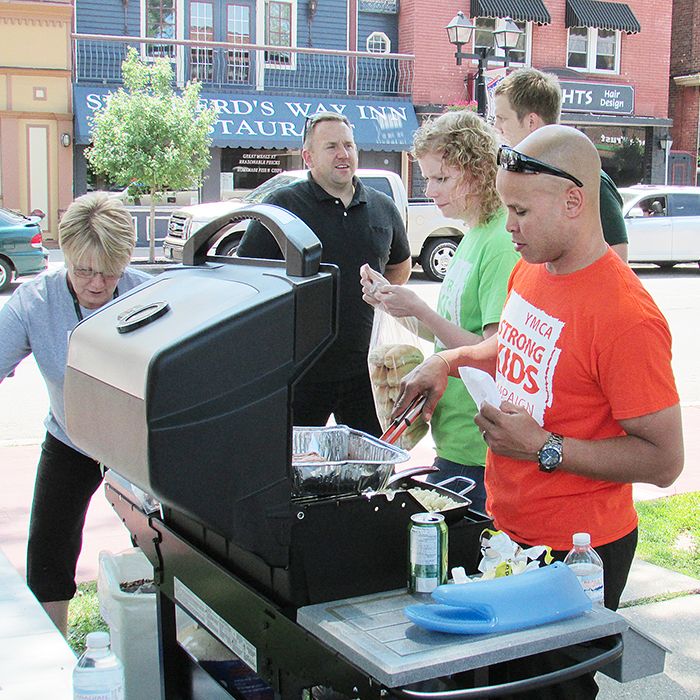 Chris Prince, right, of the YMCA, mans the grill with the help of TD’s Kelly Jones.