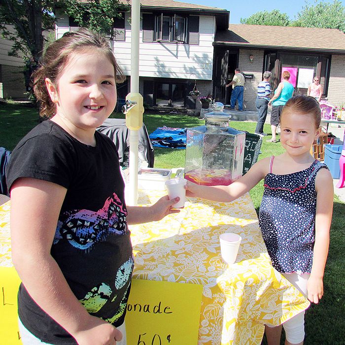 Libby Attewell, 7, right, sells a glass of pink lemonade to a customer May 31 at the annual street sale on Whippoorwill Crescent in Chatham. This is the second year Libby has sold lemonade and donates the proceeds to Ronald McDonald House in London. This year, she raised $565.