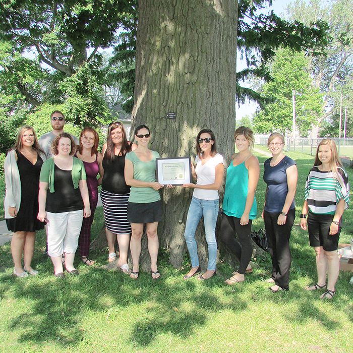 Scribendi staff accept a plaque from Kelly Johnson, right, the community trees initiative co-ordinator with the Greening Partnership. Scribendi donated $3,000 to help fund the heritage tree program in Chatham-Kent.