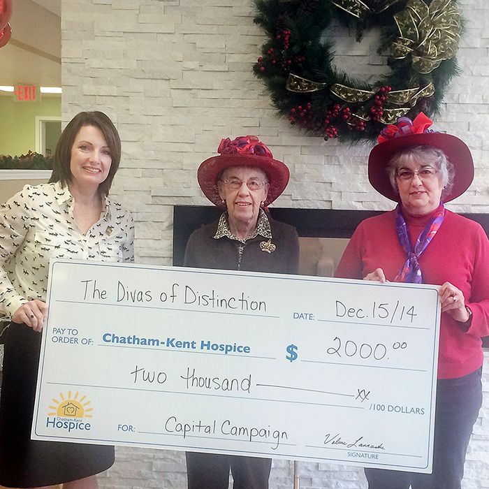Jodi Maroney of the Chatham-Kent Hospice, accepts a cheque for $2,000 from Mary An Langlois and Valerie Lancaster, two Divas of Distinction with the Red Hat Society.