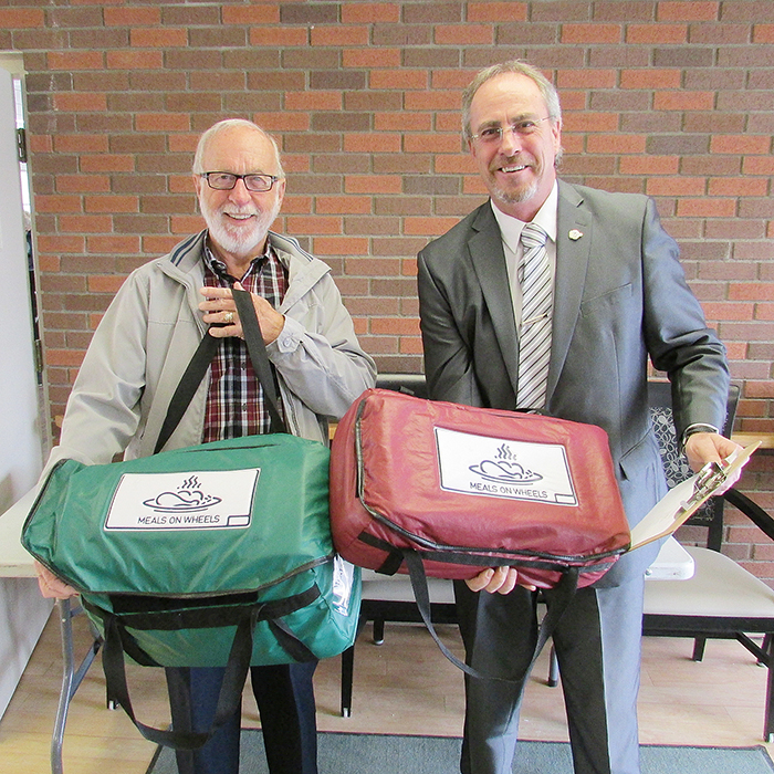 Jake Janssens, left, and Mayor Randy Hope prepare to head out Friday to deliver hot meals to seniors as part of the Meals on Wheels’ Mayors for Meals program.