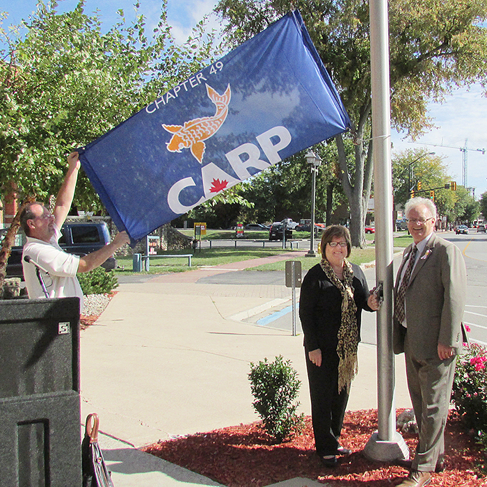 Chatham-Kent Councillor Karen Herman and local director Steve Brent prepare to raise the flag of the Canadian Association of Retired Persons during national Seniors’ Day at the Civic Centre.