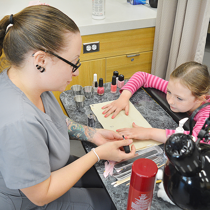 The Esthetician program at St. Clair College raised a total of $1,000 by painting nails Friday. Here student Angela Charron applies the finishing touches to eight-year-old Izzabelle Wiebe's nails.