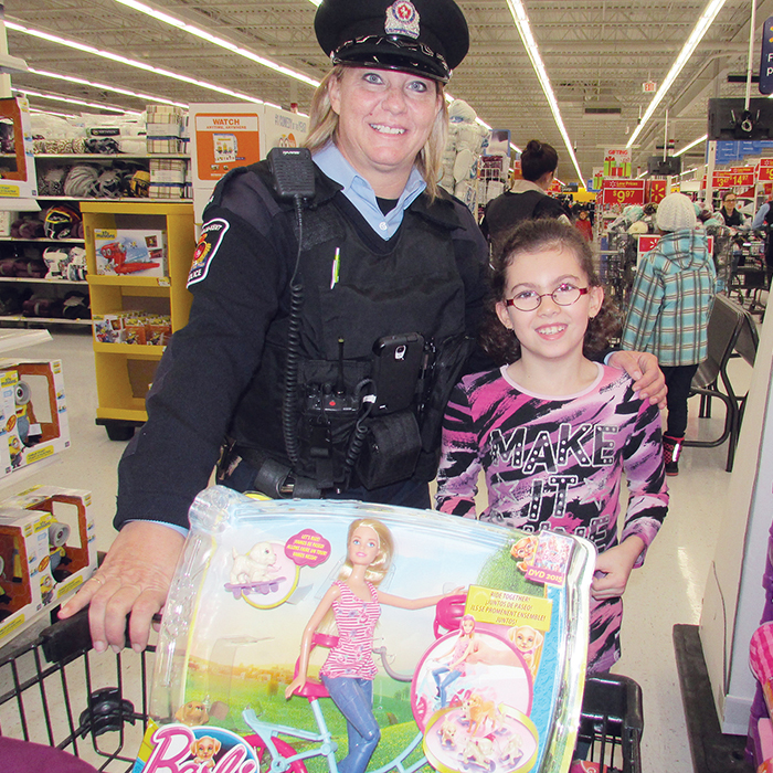 Angelica Burnett, 8, is all smiles, as she and Chatham-Kent police Spec. Const. Terry Kivell had some great fun at Shop With a Cop at WalMart on Saturday. Fifty local children paired up with area police officers to go on $100 shopping sprees for themselves and their families.