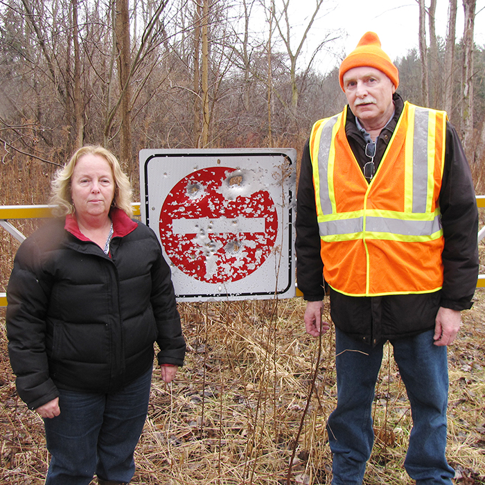 September and Malcolm MacAlpine showcase a sign on the edge of their property that's been shot up by hunters. The couple fears for their safety as poachers regularly hunt deer in an adjoining woodlot.