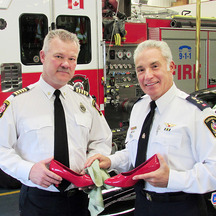 Chatham-Kent’s fire and police departments show support for this year’s Walk A Mile event sponsored by the Chatham-Kent Women’s Centre. Here C-K Fire Chief Ken Stuebing and police chief Gary Conn polish one of the red shoes that will be worn during the June event.