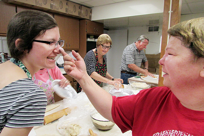 The pie women and a couple of men of Trinity Anglican Church in Blenheim are hard at work this week getting ready for Cherry Fest July 14-18, where they will sell more than 2,500 pies. Summer student Rosemary Parker, who is from Ottawa and studying to become a priest, gets a flour makeover from pie maker Marianne Blanchette.
