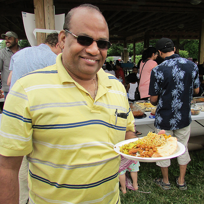 Maru Lakshmanan of the Asian-Canadian Cultural Association enjoys a meal with about 100 others at a picnic in Kingston Park on Saturday.