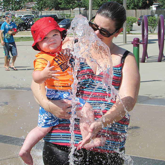 Laurie Burse and her son Benjamin, 10 months, play in a gush of water at Kingston Park’s splash pad. Burse took her son and daughter, Emily, 4, there to beat the summer heat.