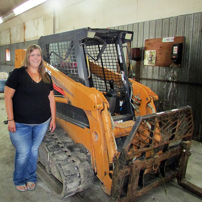 Noelle Heyink stands next to a skid steer, one of the few pieces of equipment left after thieves stole $120,000 worth of property from their Thamesville business August 20.