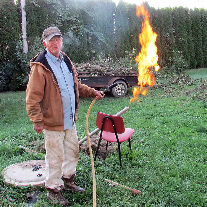 Local well driller Ken Wade burns off some methane from a Dover Twp. well he is restoring while holding a hose containing potable water. Wade said concerns about methane affecting water quality are misleading.