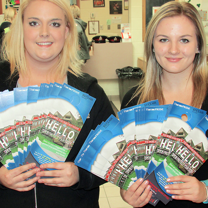 Kayla Hodgson (left) and Taylor Lorlarue show some of the 2,000 door knockers being distributed throughout the community by East Side Pride and students from the St. Clair College Police Foundations program.