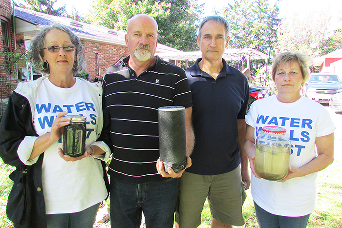 Dover resident Marc St. Pierre, left is at his wit’s end with trying to get the municipality to take his water issues seriously. He recently invited Water Wells First members Cheryl Forsyth of Eberts, far left, and Yvonne Profota, also of Eberts, to his home on Bay Line to show how bad his well water has become. Pictured with them is local activist Kevin Jakubec, middle right, who is spearheading the fight to solve the Dover well problems. The group is holding black water samples from St. Pierre’s tap as well as one of the white filters he has to purchase every two weeks for his filtration system.