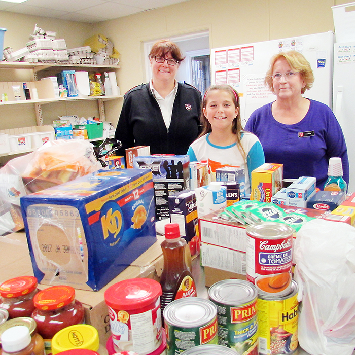 Alyah Detailleur, 10, centre, is seen with Capt. Stephanie Watkins and Bev Reeve of the Salvation Army with some of the items Alyah and her brother, Noah, 12, collected for the organization’s food bank.