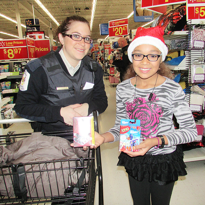 Kaitlan Elijah, 11, is all smiles with Park Warden Trena Lebedz during the annual Shop With A Cop event Saturday morning at Wal-Mart.