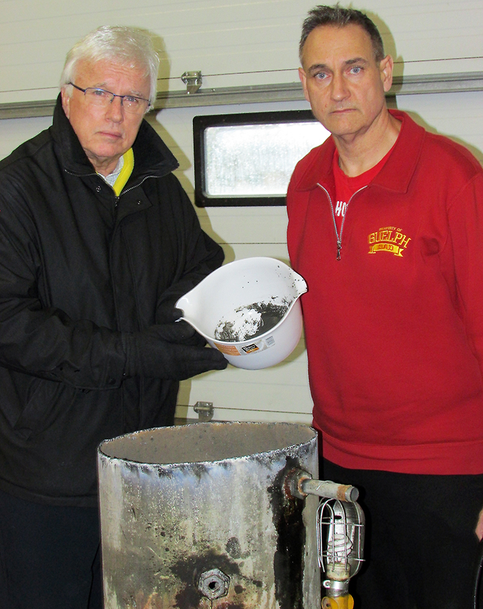 MPP Rick Nicholls gets a first-hand look at black sludge from a pressure tank of the well belonging to Dover resident Laurier Cartier, with Water Wells First spokesperson Kevin Jakubec. The toxicity of the contaminated wells are the main concern of the group. 