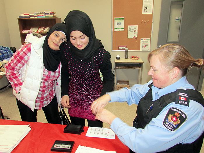 Chatham-Kent Police Service Spec. Const. Tamara Dick takes the fingerprints of Gharam Alhamad, 13, right, while her sister Fatima, 14, looks on. Block Parents offered the Fingerprint ID Clinic with the CKPS.