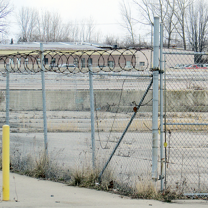 Rusted razor wire sits atop the fence surrounding the site of the former Navistar heavy truck plant in Chatham. While the company left town in 2011 and levelled the facility two years later, legal battles over employee compensation have continued.