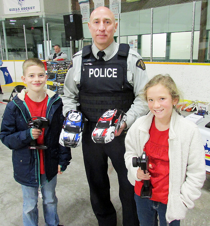 RCMP Const. Rob Allen teaches Ben Knowler and Grace Herron from St. Michael’s in Ridgetown how to drive the remote control cars at the Racing Against Drugs awareness week at Erickson Arena in Chatham on Friday.