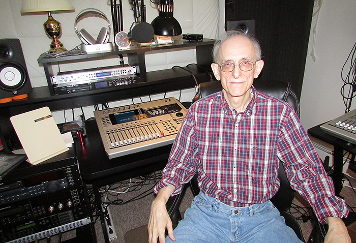 David Farquar, mastermind behind Voices In The Wind Audio Theatre, sits before his mixing station in his apartment. Voices In The Wind productions are available for download around the world.