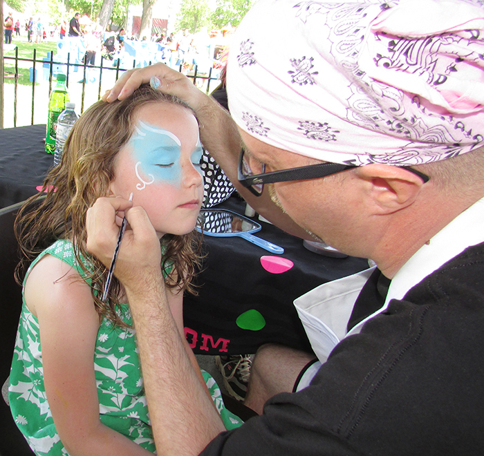 Sydney Hagmans, 7, patiently waits for Bill of Dotsy’s Entertainment to finish painting her face at the C-K Youth Festival in Tecumseh Park Saturday.
