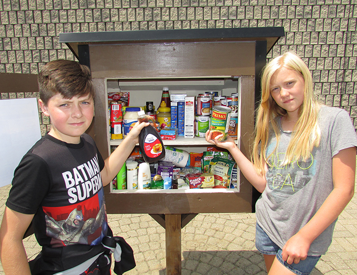 Ryan Carlson and Leah Doey, students at Queen Elizabeth Public School, deposit items into the Little Free Pantry on Adelaide Street in Chatham. Students at the school came up with the idea of a place where non-perishable food items and toiletries can be left for those in need.